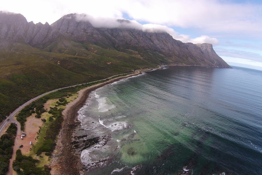 Luftbild einer gr&uuml;nen K&uuml;stenlinie mit Bergen am Meer